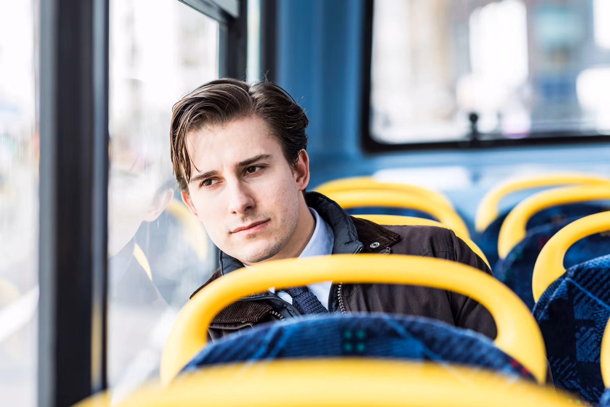 A man sits on a bus contemplating his thoughts.